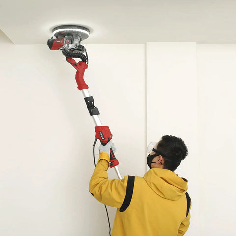 Person using Heavy Duty 810W Drywall Sander With Vacuum Attachment And LED Light on ceiling, showcasing extendable handle.