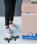 Heavy Duty Furniture Mover Dolly Set Of Four With Carbon Steel Frame And Rugged Plastic Wheels For Moving Heavy Cabinets And Appliances At Home Or In The Office Like A Real Workhorse. Set of four black steel dollies beside moving boxes and shoes.
