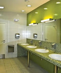 Basics LED Emergency Light With Dual Adjustable Lamp Heads For Wall Mount in a restroom, on white tile wall above sinks.