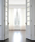 Interior view of double white doors opening towards a bright window, showcasing potential installation context for Three Pack Of 304 Stainless Steel Door Hinges In Matte Black With Non Removable Pin Heavy Duty Ball Bearing 3 Point Five Inch For Commercial And Residential Doors With One Quarter Inch Radius.