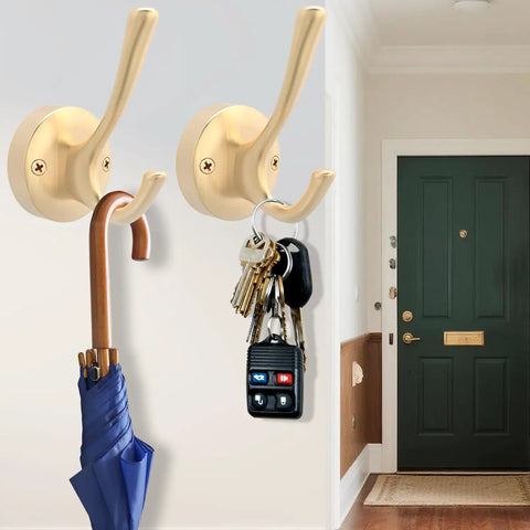 Two gold hat and coat hooks hanging an umbrella and keys in a hallway setting. Part of Gold Hat And Coat Hooks 4 Pack Heavy Duty Metal Wall Mounted Hangers For Coat Backpack Towel And Accessories In Bathroom Entryway Closet Or Garage Built From Rust Resistant Zinc Alloy With 40 Lb Capacity.