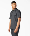 Model wearing Badass Men Short Sleeve Utility Button Down Workshirt In Charcoal, cotton polyester blend, relaxed fit, two pockets.