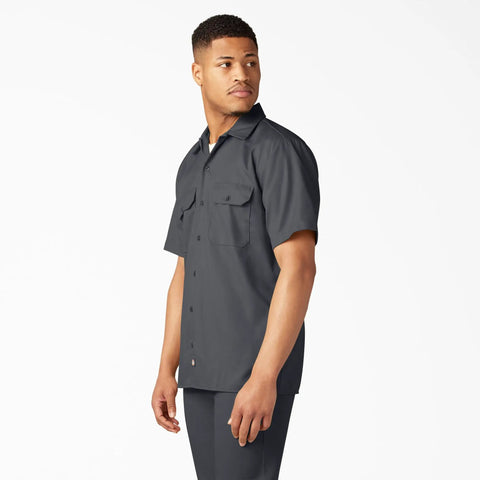 Model wearing Badass Men Short Sleeve Utility Button Down Workshirt In Charcoal, cotton polyester blend, relaxed fit, two pockets.