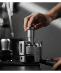 Top Shelf Espresso Needle Wdt Tool For 58mm Portafilter in use with hand applying pressure on a stainless steel base.