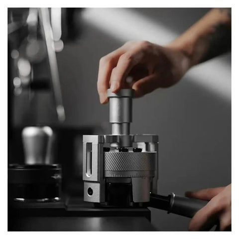 Top Shelf Espresso Needle Wdt Tool For 58mm Portafilter in use with hand applying pressure on a stainless steel base.