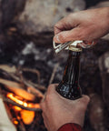 Person using Permanent Match Bottle Opener Keychain, Reusable Survival Fire Starter Striker Lighter by campfire, charcoal finish