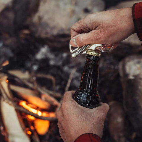 Person using Permanent Match Bottle Opener Keychain, Reusable Survival Fire Starter Striker Lighter by campfire, charcoal finish