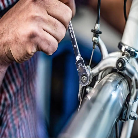 Person using Six Piece Metric Ratchet Wrench Set With Double Box End Flex Heads, 72-Tooth Gear, on a bike for repair