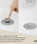 Dual Purpose Silicone Shower Drain Stopper And Hair Catcher Kills Sticky Pipe Buildup shown being pressed in a grey tone bath.