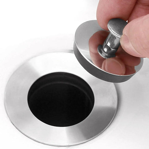 Person holding the Universals Bath Basins Waste Plug above a stainless steel sink hole, showcasing its rubber and stainless steel design.