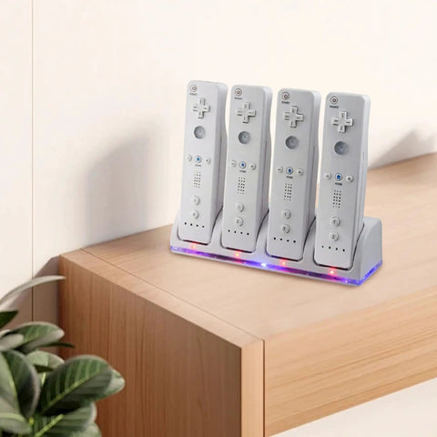 4 In 1 Battery Charging Station For Wii And Wii U Remotes With 4 Rechargeable Battery Packs And USB Cable No More Dead Batteries Fast Charge Easy Swap Keeps Your Game Time Rolling Controllers Not Included on a wooden surface, charging four remotes.