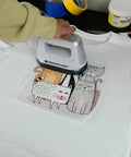 Person using heat press on white shirt with cat design, showcasing Transfer Film Roll Bundle For DTF Printing With 23.6 Inch By 328 Foot PET Film One Pound DTF Powder And Three Thick PTFE Sheets For Hot And Cold Peel Transfers On Heat Press Or Screen Printing.