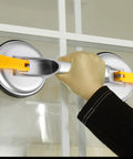 Hand using Super Heavy Duty 2 Jaw Glass Suction Cup Lifter Tool With Spring Loaded Locking Handle on glass surface.