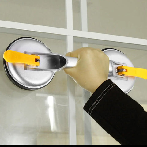 Hand using Super Heavy Duty 2 Jaw Glass Suction Cup Lifter Tool With Spring Loaded Locking Handle on glass surface.
