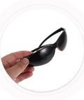 Hand holding Top Shelf Welding Goggles 4 Pack With Splash Resistant Lens And Impact Rated Frame, dark tinted for eye protection.