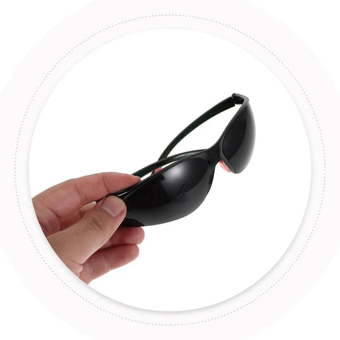 Hand holding Top Shelf Welding Goggles 4 Pack With Splash Resistant Lens And Impact Rated Frame, dark tinted for eye protection.