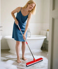 Woman cleaning bathroom floor with Heavy Duty 16.5 Inch Push Broom With 51 Inch Long Handle For Patio Garage Deck Tile And Concrete Floors Cleaning