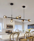Mid-Century Glass Globe Pendant Light Fixture In Black And Gold, Semi-Flush Ceiling Chandelier for Kitchen Island shown in modern kitchen