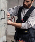 Person wearing Allround Work Tool Vest For Men With Tons Of Pockets, Built Tough Utility Vest With Adjustable Side Fit, Black XXL.