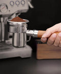 Kick Up Your Morning Vibes With This Rock Solid 58mm Bottomless Portafilter Built For Breville Dual Boiler Espresso Makers Dope Pulls And Creamy Shots Daily. Hand holding 58mm portafilter filled with ground coffee.