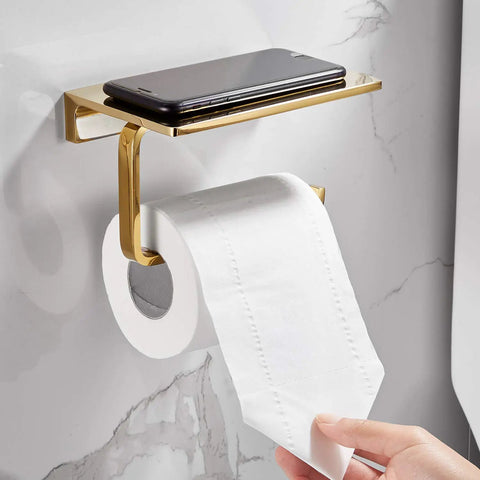 Solid Brass Toilet Paper Holder With Gold Finish, Hotel Style Tissue Roll Holder Plus Built In Cell Phone Shelf, Rust Resistant Chrome Finish, Pro Grade Heavy Duty Bathroom Organizer For Rolls Up To 5.31 Inches on a marble wall