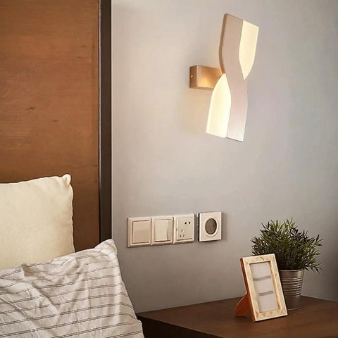 UPRENXIAO Modern Minimalist Nordic Led Wall Sconce Wavy Twisted Design Baked installed above a bed with soft light.