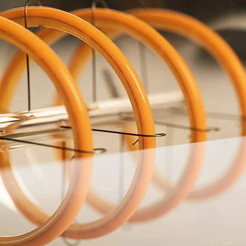 Close-up of Cozy Amber Glow T10 LED Filament Bulbs 2200K Warm White reflecting in a glossy surface, showing tubular shape and wiring.