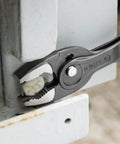 10 Inch Pliers With Front And Side Grips For Stripped Screws And Bolts, gripping a bolt on a metal surface in workshop