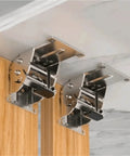 Two silver folding leg brackets with screws mounted under a wood cabinet top; metal, 180-degree fold.