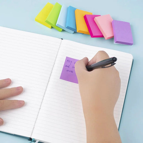 Person writing on purple mini sticky note from a set of bright colors, mini sticky notes one point five by two inches.