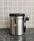Rock Solid 304 Stainless Steel Coffee Canister Featuring One Way Degassing Valve And Rotatable Date Tracker Keeps Your Daily Grind Fresh And Legit Snap Tight Airtight Tea Storage Container on a countertop.