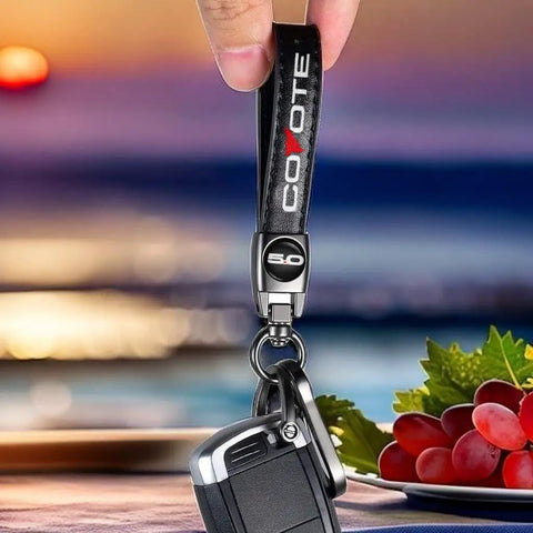 Premium Leather Car Keychain With Coyote 5 0 Emblem and Built In Screwdriver Tool Heavy Duty Alloy Ring for Ford Mustang, held by hand.