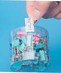 Hand holding tagged 4000 pcs small pricing labels on rolls near colorful binder clips for retail pricing machines.