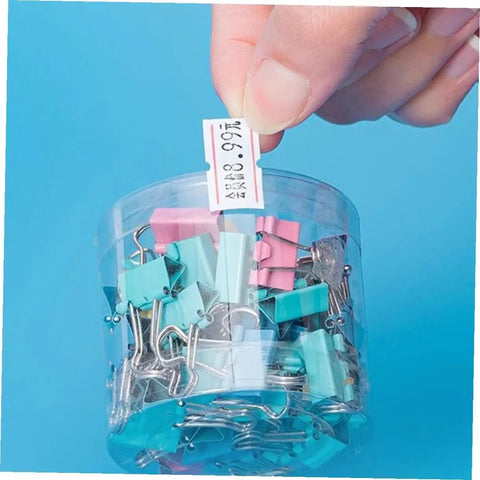 Hand holding tagged 4000 pcs small pricing labels on rolls near colorful binder clips for retail pricing machines.