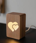 Wooden night light with illuminated double heart design for ambient room lighting.