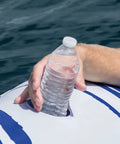 Hand placing water bottle in cup holder of Blue Tropic Inflatable Five Person Pool Island Lounge Raft With Backrests Built In Cooler And Four Cupholders For Lake Or Pool Day Party And Relaxation For Big Group Summer Fun.