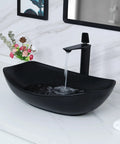 Black ceramic vessel sink with faucet in a modern bathroom setting with floral decoration on the white vanity countertop.