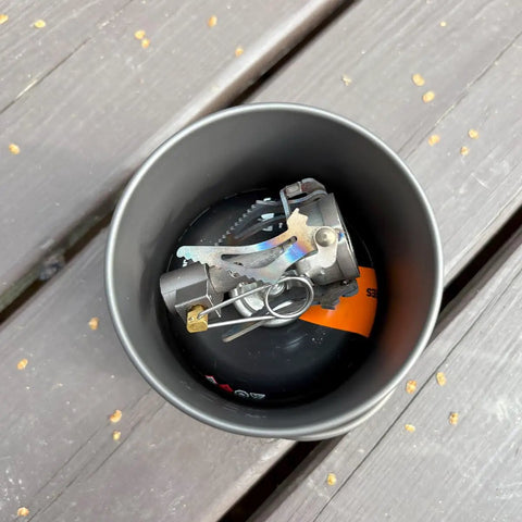 Top view of Ultralight Titanium 750ml Camp Pot with lid, stove inside, on wooden surface for solo hikes and backpacking