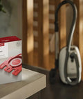 Box of AirClean Dust Bags Type FJM HyClean for vacuum cleaners beside a Miele vacuum cleaner in a home setting.