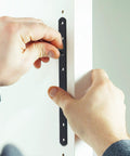 Person installing a Stainless Steel Flat Bracket Set For Wood Handrails And Stair Rails, black sleek brace plate being screwed in