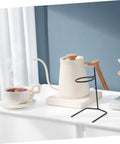 Kick Up Your Morning Brew Game With This Slick Two Piece Coffee Dripper Stand. Black steel coffee dripper stand beside cup.