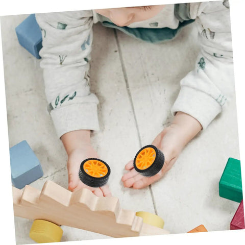 Child playing with two orange rubber tires from 10 Pcs DIY Car Wheels For Kids Toy Replacement Small Rubber Tires With 0.08 In Axle Hole For Model Cars And Science Projects Durable Craft Accessories For Hobbyists And Classroom Projects