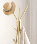 Top view of coat rack with 12 hooks freestanding hall tree in gold finish with hat and coat displayed in modern room.