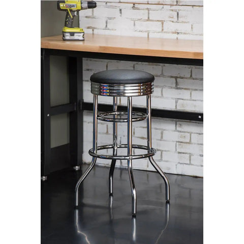 Heavy Duty 30 Inch Backless Swivel Bar Stool With Chrome Finish And Faux Leather Seat For Kitchen Garage Or Workshop, Supports Up To 300 Pounds, Black next to a workbench