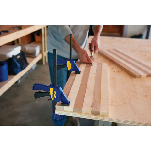 Two Six Inch Mini Bar Clamps securing wood pieces on a workbench, demonstrating quick release trigger for woodworking projects.