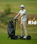 Man riding Electric Four Wheel Foldable Golf Cart Trolley With Easy Push Or Ride Options In Classic Black Trim on grass.