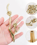 Slick Twig Drawer Pulls In Polished Brass Plum Blossom Branch Handle, shown in hand, highlighting flower detail and installation.