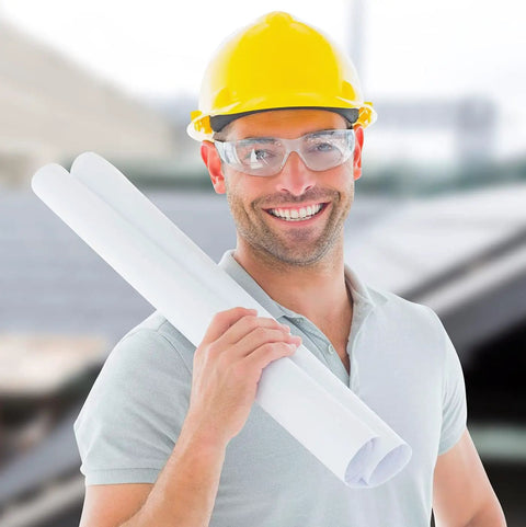 Man wearing yellow hard hat and clear anti-fog safety glasses, holding blueprints, showcasing 12 Pack Clear Anti Fog Safety Glasses With Wraparound Lenses.