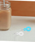 Glass tumbler with straw next to blue and white Six Pack Silicone Straw Charm Adapters For Tumblers, Stylish And Fun Straw Pendants