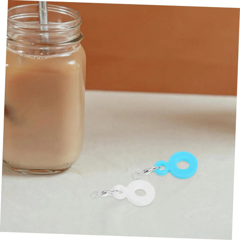 Glass tumbler with straw next to blue and white Six Pack Silicone Straw Charm Adapters For Tumblers, Stylish And Fun Straw Pendants